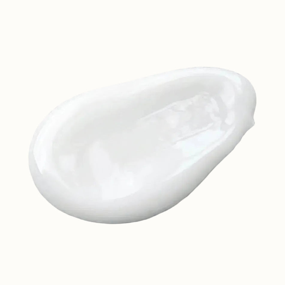 A glossy white cream or lotion smear on a gray and white checkerboard transparency background.